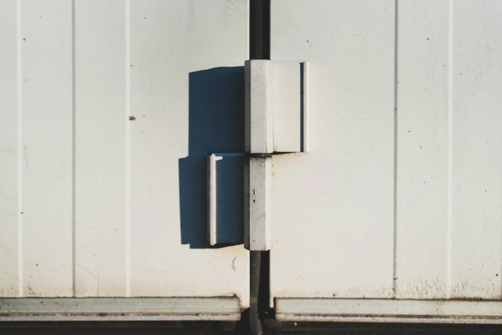 Närbild på gångjärnen på en Torverk vikport monterad 1989