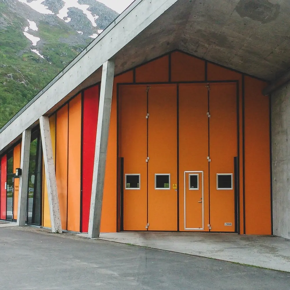 Orange folding door placed in a recessed niche, sheltered from the wind